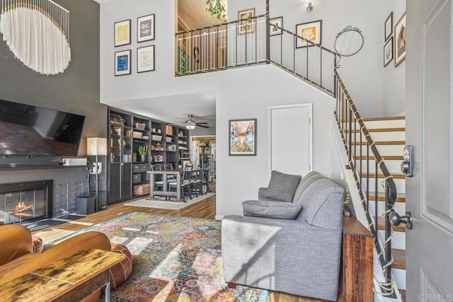 living room with a towering ceiling, wood-type flooring, and ceiling fan