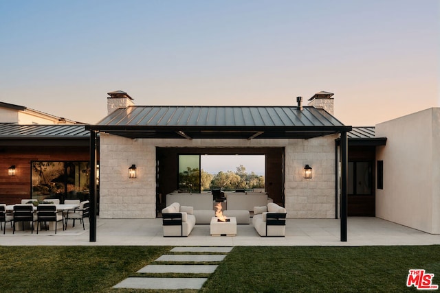 back house at dusk with a patio, area for grilling, and a lawn