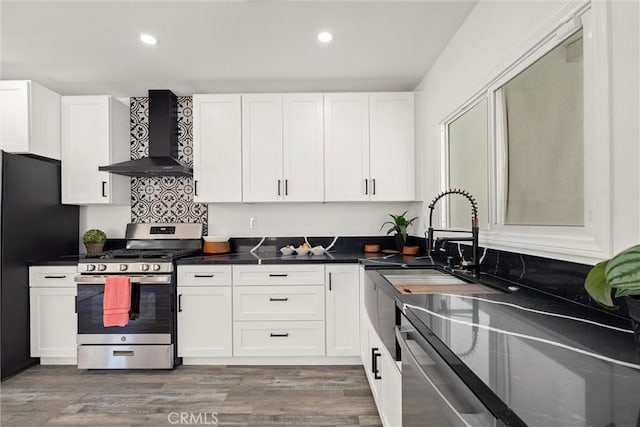 kitchen with white cabinetry, wall chimney exhaust hood, stainless steel appliances, and wood-type flooring