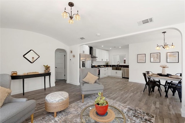 living room with vaulted ceiling, dark wood-type flooring, sink, and a chandelier