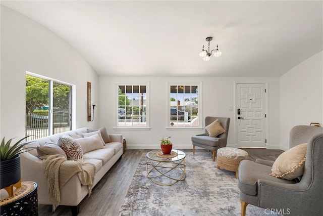 living room featuring wood-type flooring, vaulted ceiling, and a notable chandelier