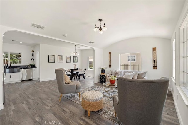 living room featuring lofted ceiling, wood-type flooring, sink, and a notable chandelier