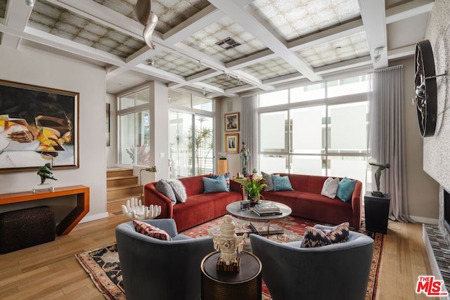 living room featuring beamed ceiling, coffered ceiling, and light hardwood / wood-style floors