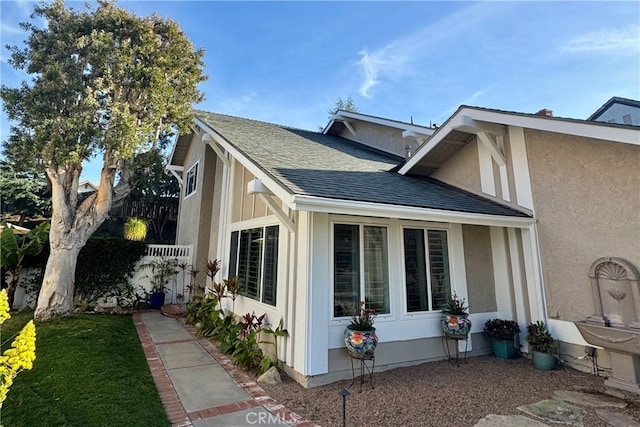 view of home's exterior with roof with shingles and stucco siding