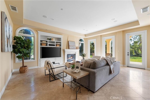 living room with plenty of natural light, a raised ceiling, and built in features