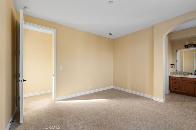 unfurnished bedroom featuring connected bathroom, sink, and light colored carpet