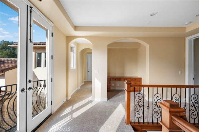 hallway with a healthy amount of sunlight and light carpet