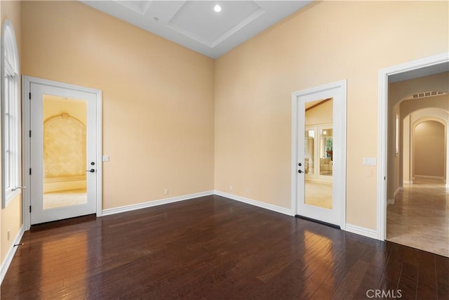 spare room with coffered ceiling and dark hardwood / wood-style flooring