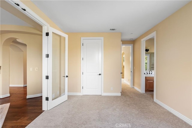 unfurnished bedroom featuring sink, ensuite bathroom, and carpet