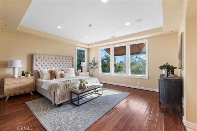 bedroom featuring dark hardwood / wood-style floors and a tray ceiling