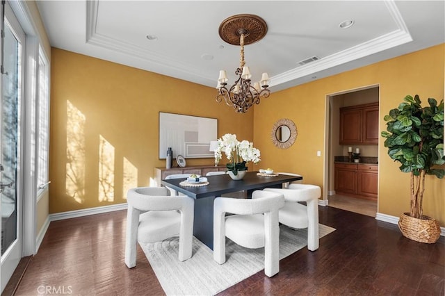 dining area with an inviting chandelier, a tray ceiling, dark wood-type flooring, and ornamental molding