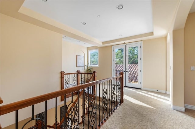 hallway with french doors, carpet flooring, and a tray ceiling