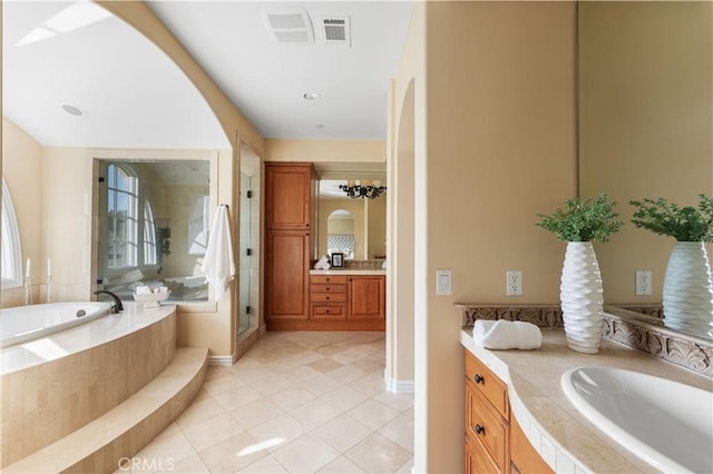 bathroom with vanity, tiled bath, and tile patterned flooring