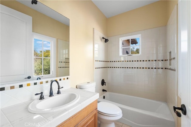 full bathroom featuring tiled shower / bath, vanity, and toilet