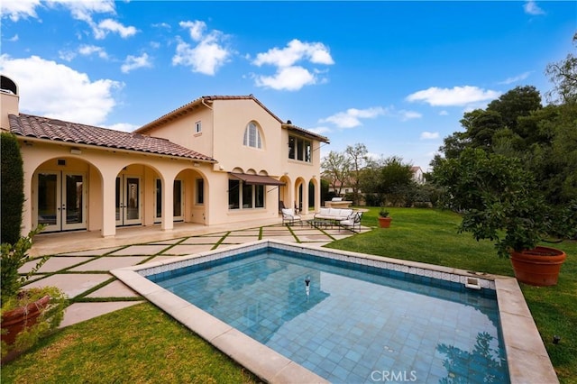 rear view of house with french doors, a patio, and a lawn