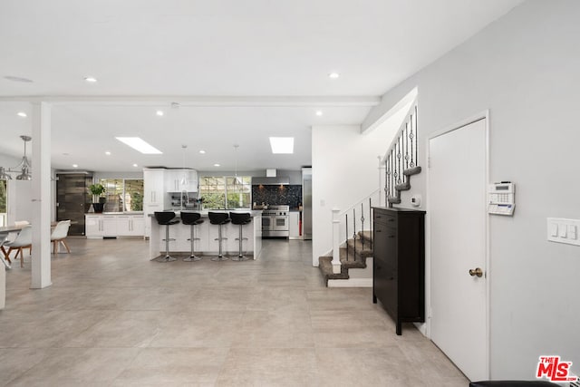 kitchen with wall chimney range hood, a breakfast bar area, white cabinetry, a center island, and range with two ovens