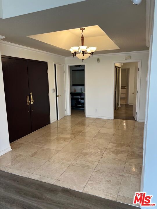 foyer featuring ornamental molding and a chandelier