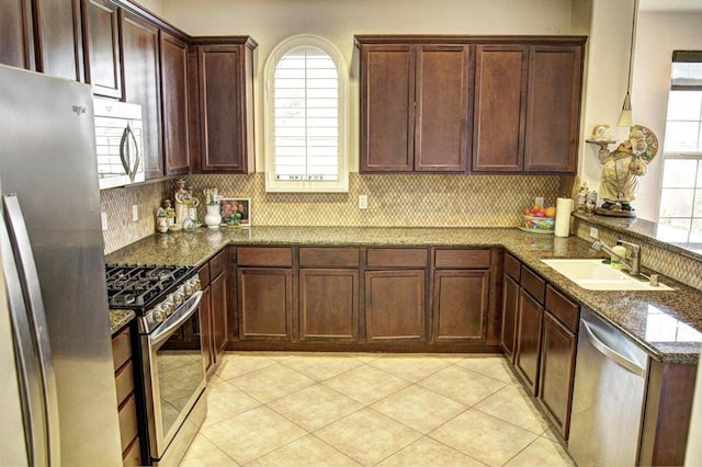 kitchen featuring stainless steel appliances, tasteful backsplash, sink, and dark stone countertops