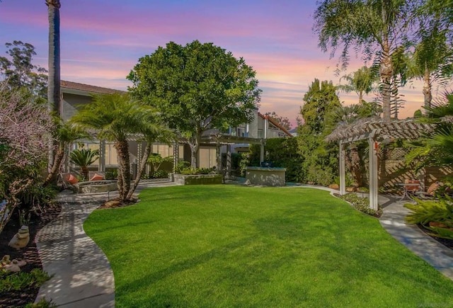 yard at dusk featuring a pergola