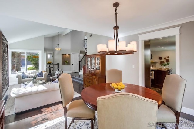 dining space with hardwood / wood-style flooring, lofted ceiling, and an inviting chandelier