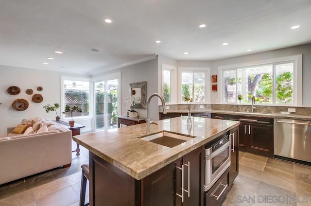 kitchen featuring plenty of natural light, dishwasher, sink, and a center island with sink