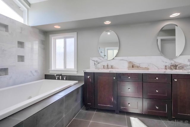 bathroom with tile patterned flooring, vanity, and a relaxing tiled tub