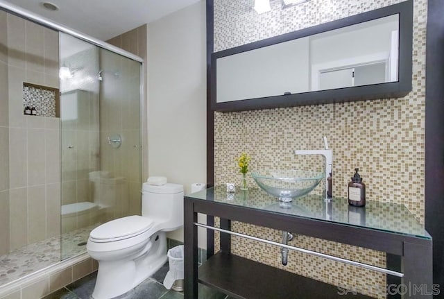 bathroom featuring tasteful backsplash, vanity, toilet, and a shower with door