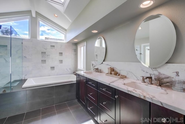 bathroom featuring lofted ceiling with skylight, tasteful backsplash, shower with separate bathtub, vanity, and tile patterned flooring