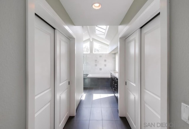 hall featuring dark tile patterned flooring and a skylight