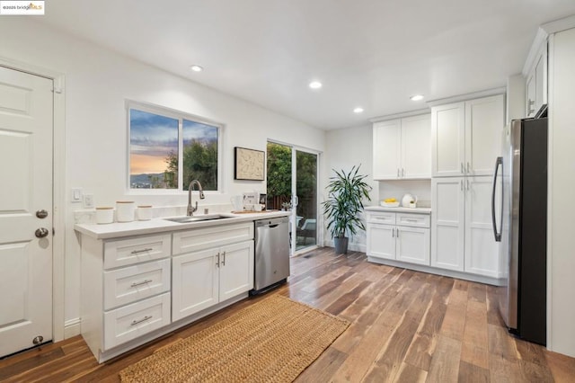 kitchen featuring hardwood / wood-style flooring, white cabinetry, appliances with stainless steel finishes, and sink