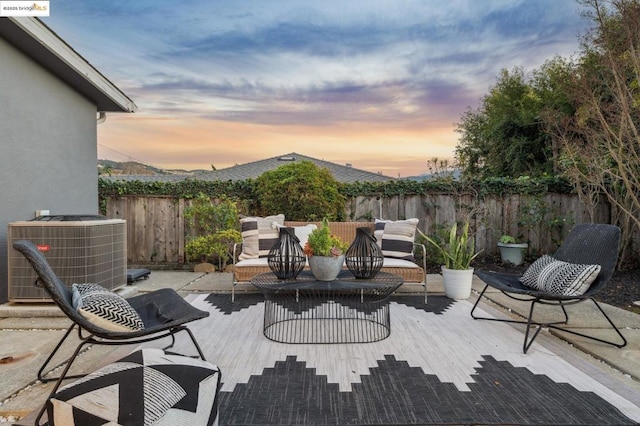 patio terrace at dusk with an outdoor living space and central air condition unit