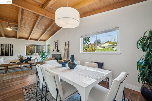 dining space with dark hardwood / wood-style flooring, vaulted ceiling with beams, wood ceiling, and a tiled fireplace