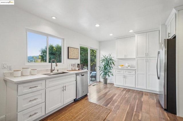 kitchen featuring hardwood / wood-style flooring, appliances with stainless steel finishes, sink, and white cabinets