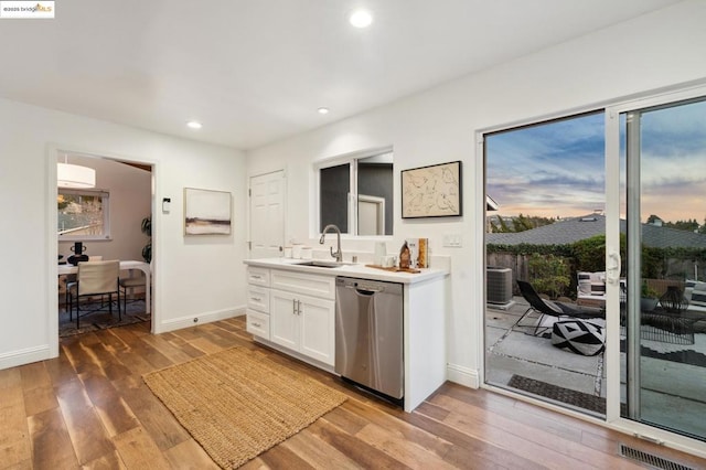 kitchen featuring sink, dishwasher, white cabinetry, wood-type flooring, and a healthy amount of sunlight