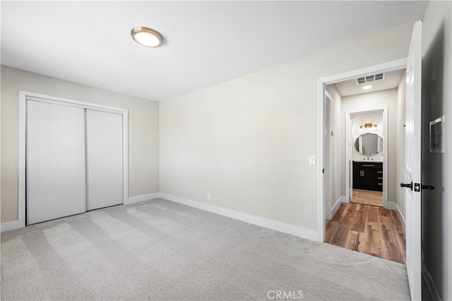 unfurnished bedroom with light colored carpet and a closet