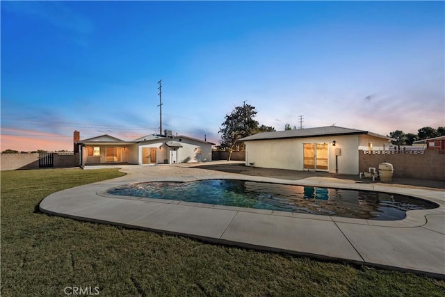 pool at dusk with a yard and a patio area