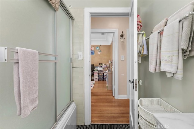 bathroom with hardwood / wood-style flooring and enclosed tub / shower combo