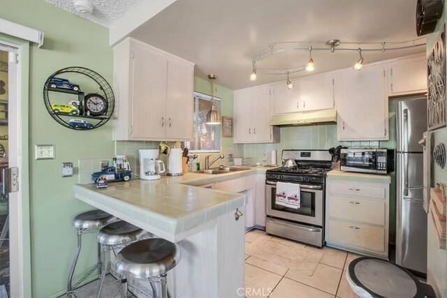 kitchen featuring sink, stainless steel appliances, a kitchen bar, decorative backsplash, and kitchen peninsula