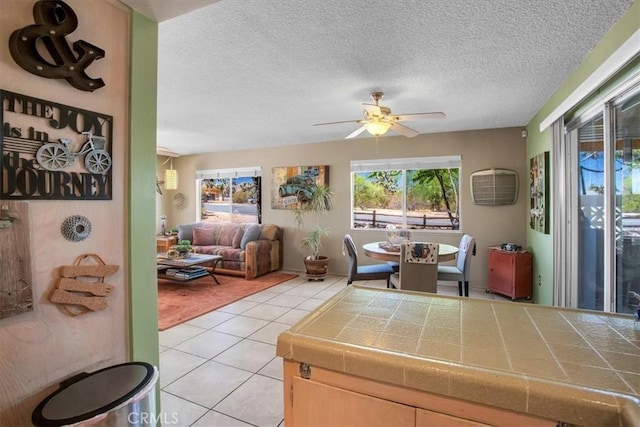 living room featuring ceiling fan, a textured ceiling, and light tile patterned floors