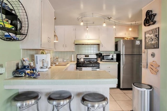 kitchen with sink, white cabinetry, tasteful backsplash, tile countertops, and stainless steel appliances