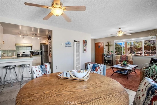 dining room featuring ceiling fan, a textured ceiling, and light tile patterned floors