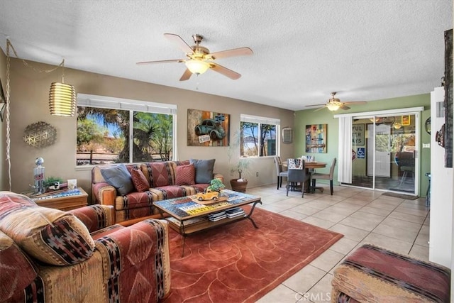 living room with ceiling fan, a textured ceiling, and light tile patterned floors