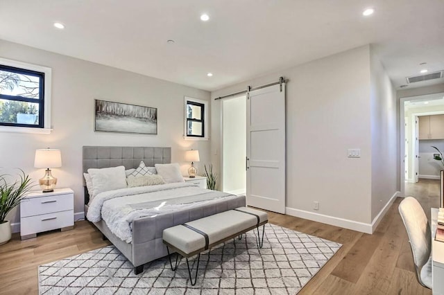 bedroom featuring light hardwood / wood-style flooring and a barn door