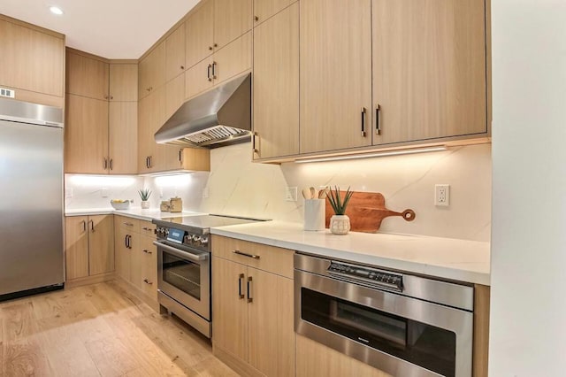 kitchen featuring built in appliances, light hardwood / wood-style floors, decorative backsplash, and light brown cabinets