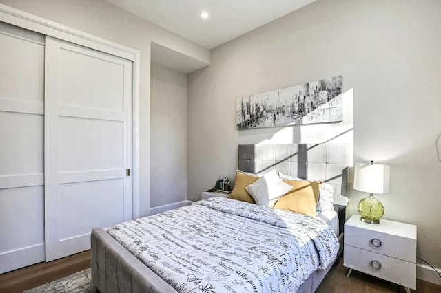 bedroom with dark hardwood / wood-style flooring and a closet