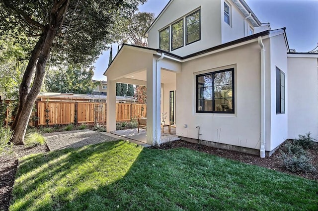 rear view of house with a patio area and a lawn