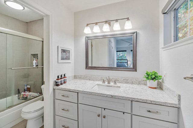 full bathroom with bath / shower combo with glass door, vanity, and toilet