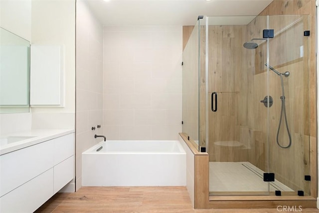 bathroom featuring plus walk in shower, wood-type flooring, and vanity