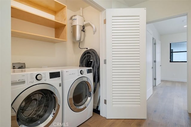 clothes washing area featuring washing machine and dryer and light hardwood / wood-style flooring