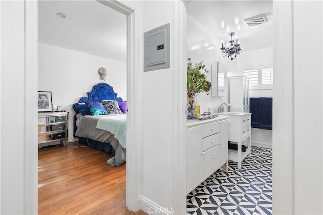 bathroom featuring hardwood / wood-style floors, electric panel, and a chandelier